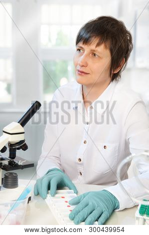 Middle-aged Female Scientist Or Tech Working With Microscope In Research Facility