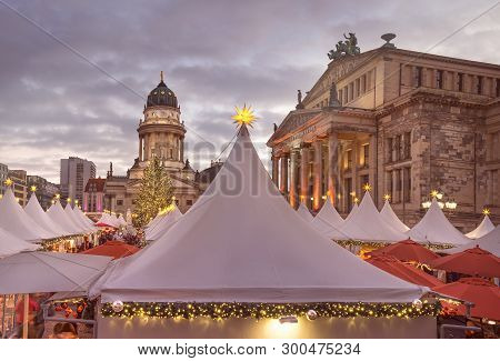 Chtristmas Market In Gandarmenmarkt In Berlin Early In The Evening Under Dramatic Sky. Panoramic Ima