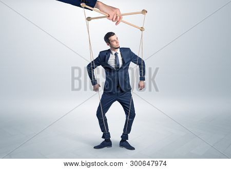 Puppet businessman in an empty room leaded by a huge hand