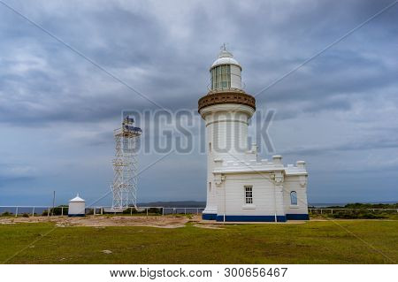 White Lighthouse Building Architecture With Overcast Sky On The Background. Point Perpendicular Ligh