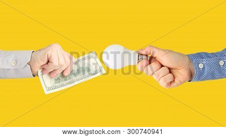 Two Hands With Dollar Bills And An Led Lamp On A Bright Orange Background. Payment For Electricity. 