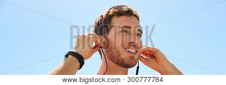 Runner man getting ready for run putting on wireless earphones with bluetooth technology for headphones smartphone communication for listening music during running exercise. Happy athlete.