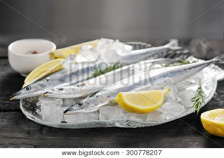 Raw Saury On A Glass Dish In The Form Of Fish With Rosemary And Lemon