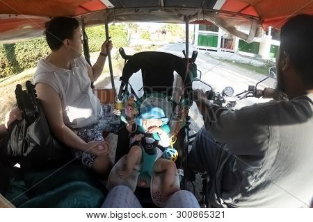 Phuket, Thailand - February 19, 2019: The Unsafe Transportation Of A Small Child In A Baby Stroller 