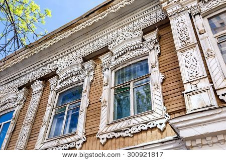 Russian Traditional Wooden Architecture. Facade Of An Old House Decorated With Wooden Carvings, Plat