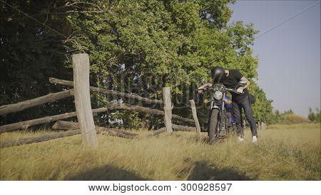Motorcyclist Pulls A Broken Bike. Motorcyclist Rolls His Motorcycle. Motorcyclist Goes Near His Bike