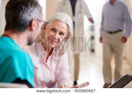 Doctor Welcoming To Senior Female Patient Being Admitted To Hospital
