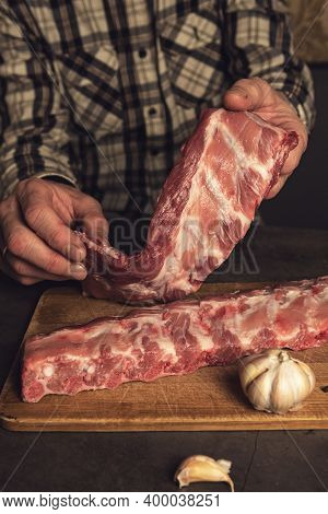 Fresh Pork Ribs, Cooking For Frying With Garlic, On A Wooden Background Top View. Male Hands Holding