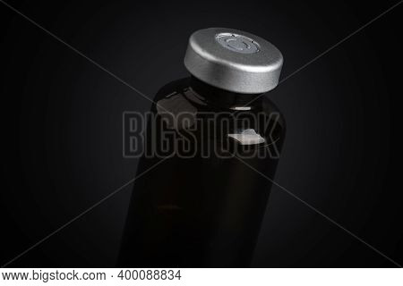 A Macro Shot With Selective Focus Of An Amber Color Vaccine Injection Bottle Set On A Dramatic Black