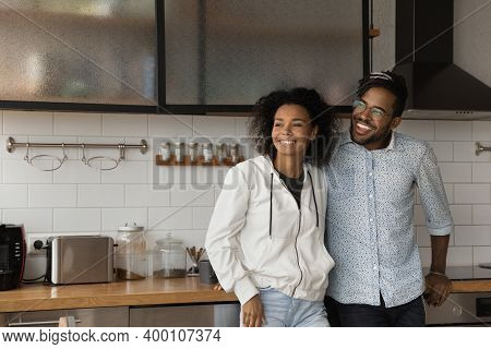 Happy Biracial Couple Dreaming In New Home Kitchen