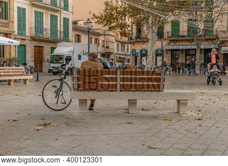Llucmajor, Spain: December 17 2020: Older Person Sitting On A Public Bench With A Face Mask On His B