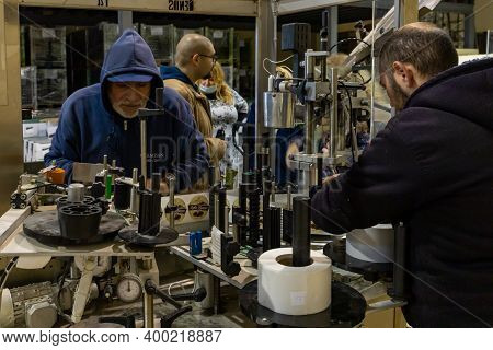Bethlehem, Israel, December 09, 2020 : Workers Service A Machine For Applying Stickers On Bottles In