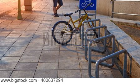 Selective Focus At The Old Bicycle Parked In Row Of Stand Bike Parking Rack With Blue Bicycle Parkin