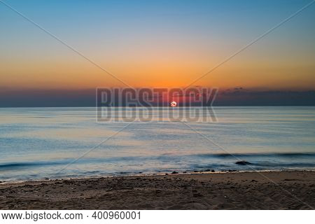 Sunrise Over Calm Sea. Dawn Over Horizon, Ocean, Water. Clear Sky. The Sun Rises Over The Beach, Coa