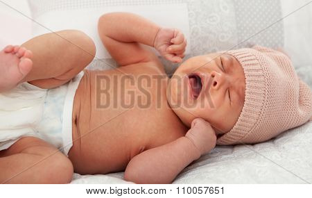 Beautiful baby in diaper with wool cap crying