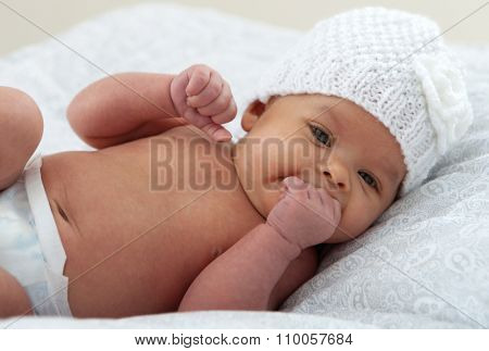 Beautiful baby with wool cap sucking her hand