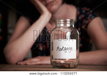 Depressed Woman Looking At Jar Labelled Mortgage