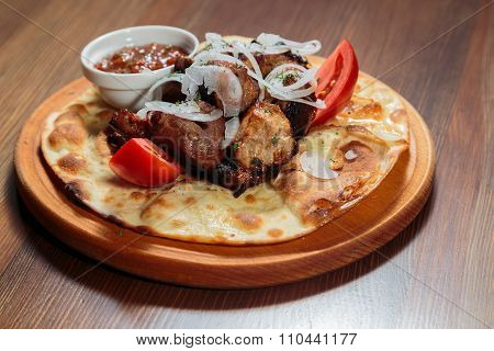 Beautifully exposed roasted meat on pita bread with sauce and pepper.