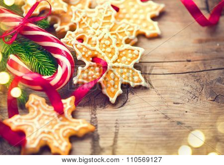 Christmas Holiday Background with Gingerbread cookies, Candy Cane and evergreens border over wooden table. Christmas and New year food. Christmas decoration and sweets on wood background