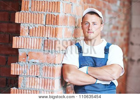 Construction worker. Mason bricklayer standing near brickwall at construction site