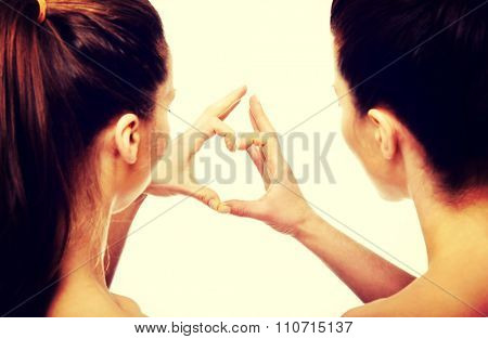 Two beautiful women making heart with fingers.
