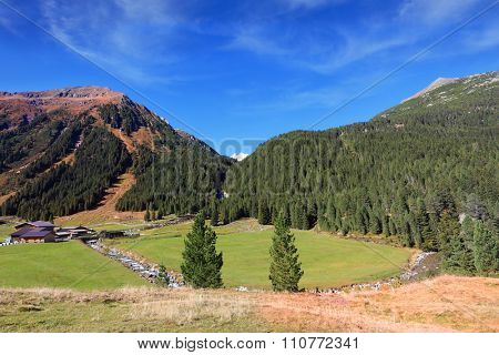 Some fast transparent streamlets connect to the rough river. Hillsides of the Alpine valley are covered with the dense coniferous forest