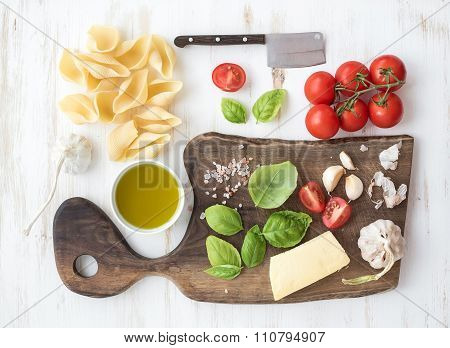 Ingredients for cooking pasta. Conchiglioni, basil leaves, cherry-tomatoes, Parmesan cheese, olive o