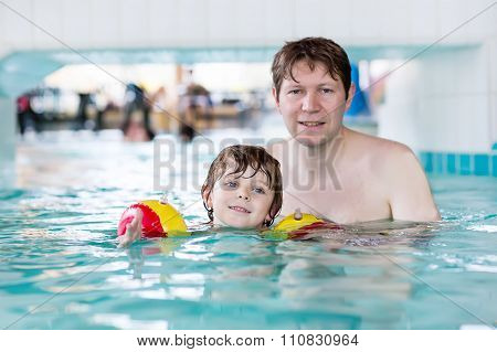 Cute little boy and his father having fun in swimming pool