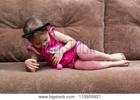 Little Girl With Cat Face Painting Play Ball On Couch