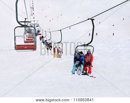 Skiers And Snowboarders On Ski Lift Against Winter Mountain Landscape