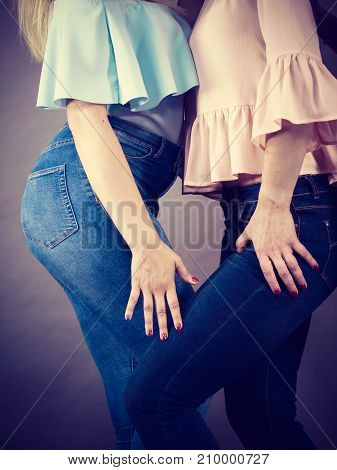 Two unrecognizable women having fashionable outfits blue jeans and colorful shirts. Fashion and clothing concept.