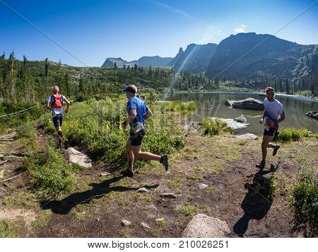 ERGAKI, RUSSIA - AUGUST 05 2017: Several athletes run through the mountains, participants trailing the SKAYRANFEST competition on August 5, 2017 in the Ergaki National Park, Russia