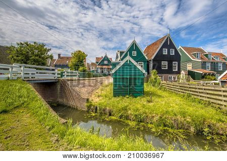 Characteristic Dutch Village Scene With Wooden Houses And Bridge Over Canal