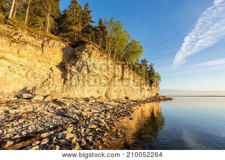 Sunset on the beach. Limestone cliff in the sea under blue sky and white clouds. Kesselaid a small island in Estonia. Nordic countries Europe
