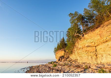 Sunset on the beach. Limestone cliff in the sea under blue sky and white clouds. Kesselaid a small island in Estonia. Nordic countries Europe