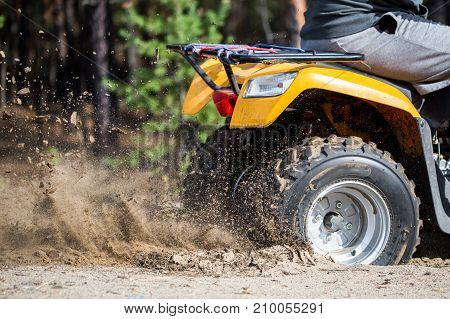 An Atv Quadbike Get Stuck In A Sandy Road Near Forest And Having Wheel-spin Making A Spray Of Sand