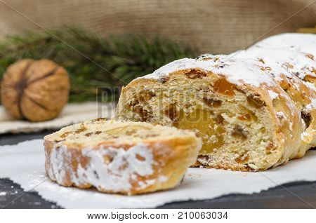 Christmas stollen on wooden background. Traditional Christmas festive pastry dessert. Stollen for Christmas. Stollen cake slice with cap of milk. Traditional Christmas stollen German festive dessert. Stollen cake cut. Christmas food card. Traditional Chri