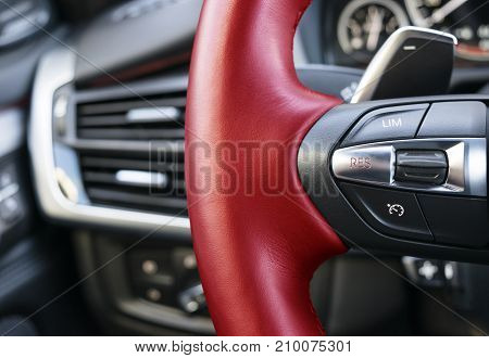 Cruise control buttons on the red steering wheel of a modern car car interior details