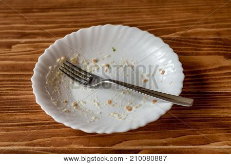 Empty plate with food remnants after meal on a wooden table