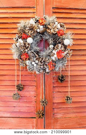 Christmas wreath hanging on wooden blinds. red shutters or door