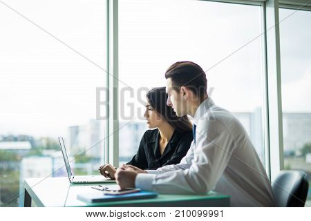 Business People Having Meeting Around Table In Modern Office Against Windows.