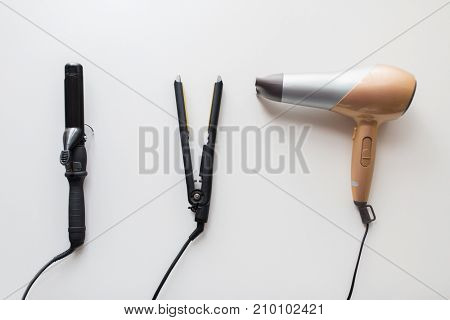 hair tools, beauty and hairdressing concept - hairdryer, hot styler and curling iron or tongs on white background