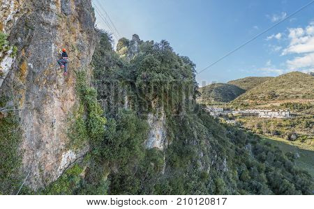 Unrecognizable tourist woman climbing up a via ferrata on mountain in sunny day