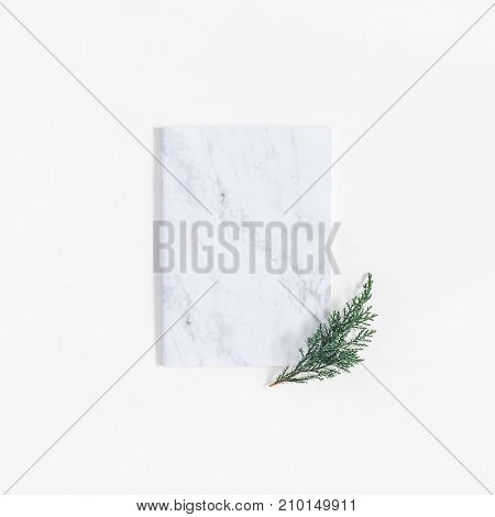 Christmas minimal composition. Marble notebook and pine branches on white background. Christmas winter new year concept. Flat lay top view copy space square