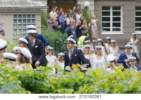 STOCKHOLM SWEDEN - JUN 13 2017: Happy teenagers wearing graduation caps running out from school after graduation at the dance school BalettakademienJune 13 2017StockholmSweden