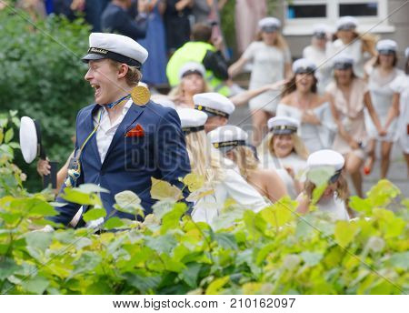 Stockholm Sweden - Jun 13 2017: Happy Teenagers Wearing Graduation Caps Running Out From School Afte
