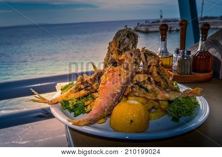 Breaded mullet fillets fried on lettuce at a restaurant in Crete