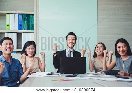 Happy Successful multiracial business team giving a high fives gesture as they laugh and cheer their success.