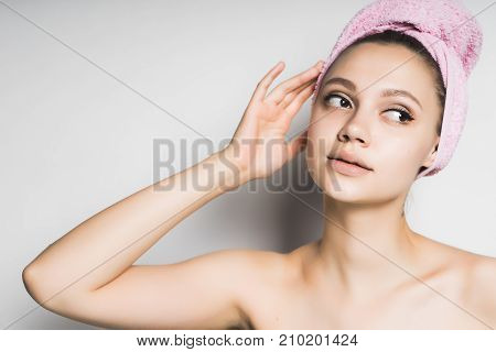 young beautiful girl with clean skin, pink towel on her head looking away thoughtfully
