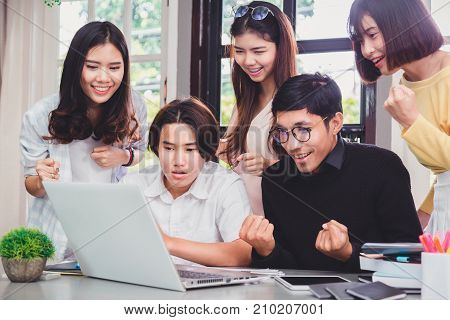 Group of young euphoric students watching exam results in a laptop in a table of an university .